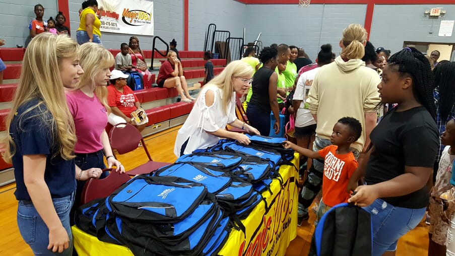 Michles & Booth handing out backpacks